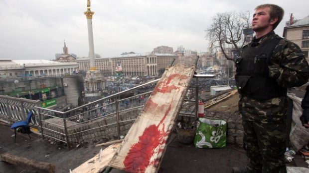 Protivládní demonstrant stojí v Kyjevě u nosítek pro zraněné