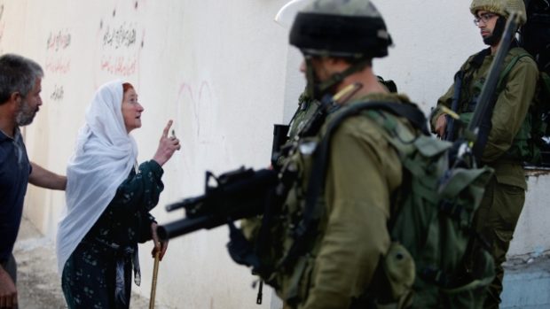 Palestinský Nábulus. Izraelský voják hovoří s palestinskou ženou