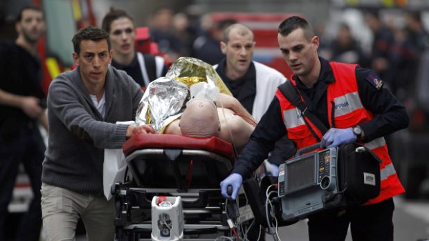 Zdravotníci odvážejí zraněného po střelbě v redakci Charlie Hebdo