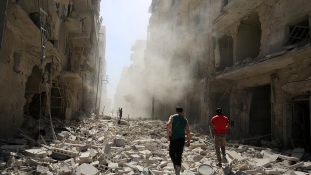 Muži prochází nálety poničeným Aleppem
