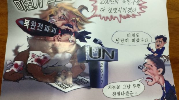 Severokorejský propagandistický plakát: Trump u řečnického pultu OSN s psím tělem, v ústech má atomovou bombu s textem „Zcela znič Severní Koreu&quot;.