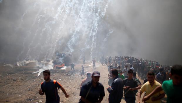 Palestinci v Pásmu Gazy prchají před slzným plynem.