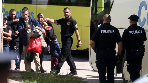 Uprchlíci za dohledu bosenské policie vycházejí z autobusu v uprchlickém centru v Salakovci poblíž Mostaru (18. května 2018).