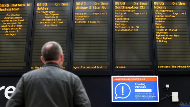 Pasažér dívající se na odjezdovou tabuli v den stávek železničních odborů ve Velké Británii.