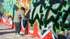 Mladí lidé sprejují po zdi, která kdysi dělila východní a Západní Berlín