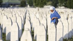 Žena truchlí za oběti srebrenického masakru uprostřed dlouhé řady náhrobků v patmátníku Srebrenica-Potočari