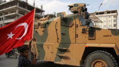 Chlapec s tureckou vlajkou vyprovází armádní vozidlo v pohraničním městě Akçakale