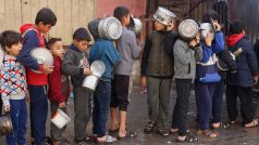 Palestinské děti čekají ve frontě na jídlo uvařené v charitativní kuchyni