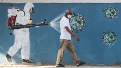 Obyvatel Rio de Janeira prochází kolem graffiti, kde je je obličej prezidenta Jaira Bolsonara vyobrazen jako koronavirus