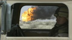 Američtí vojáci projíždí kolem hořícího ropného vrtu, zapáleného ustupující iráckou armádou, 22. března 2003
