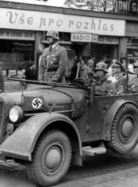 &quot;Vše pro rozhlas&quot;: auto s policejním šéfem a říšským sekretářem protektorátu K. H. Frankem (sedící vzadu) jede kolem obchodu s rozhlasovými přijímači, po 15. březnu 1939