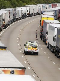 Policejní auto projíždí podél kolony kamionů na dálnici k terminálu v Doveru