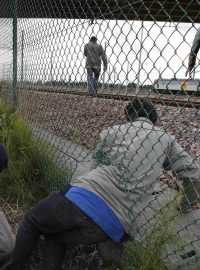 Migranti prolézají nedaleko Calais dírou v plotě. Chtějí se dostat do Eurotunelu z Francie do Velké Británie