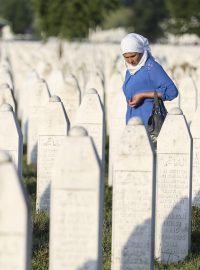 Žena truchlí za oběti srebrenického masakru uprostřed dlouhé řady náhrobků v patmátníku Srebrenica-Potočari