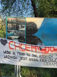 Na pravém břehu řeky Olše v polském Těšíně stojí na nábřeží osamocený transparent s nápisem: „Chceme do práce.“