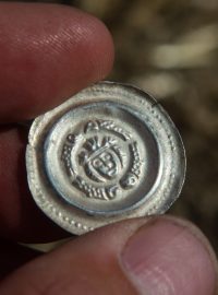 Archeologové našli na Písecku stovky mincí ze 13. století. Na mincích je hlava panovníka a ryby v kruhu kolem.