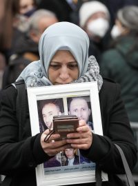 Žena stojí před budovou soudu v německém Koblenzu a drží fotografie svých pěti bratrů, kteří zemřeli v Sýrii