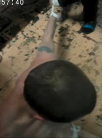 Jedno z videí zachycuje, jak na zemi leží nahý spoutaný vězeň, kterému na hlavu močí jeden z mužů stojících kolem něj